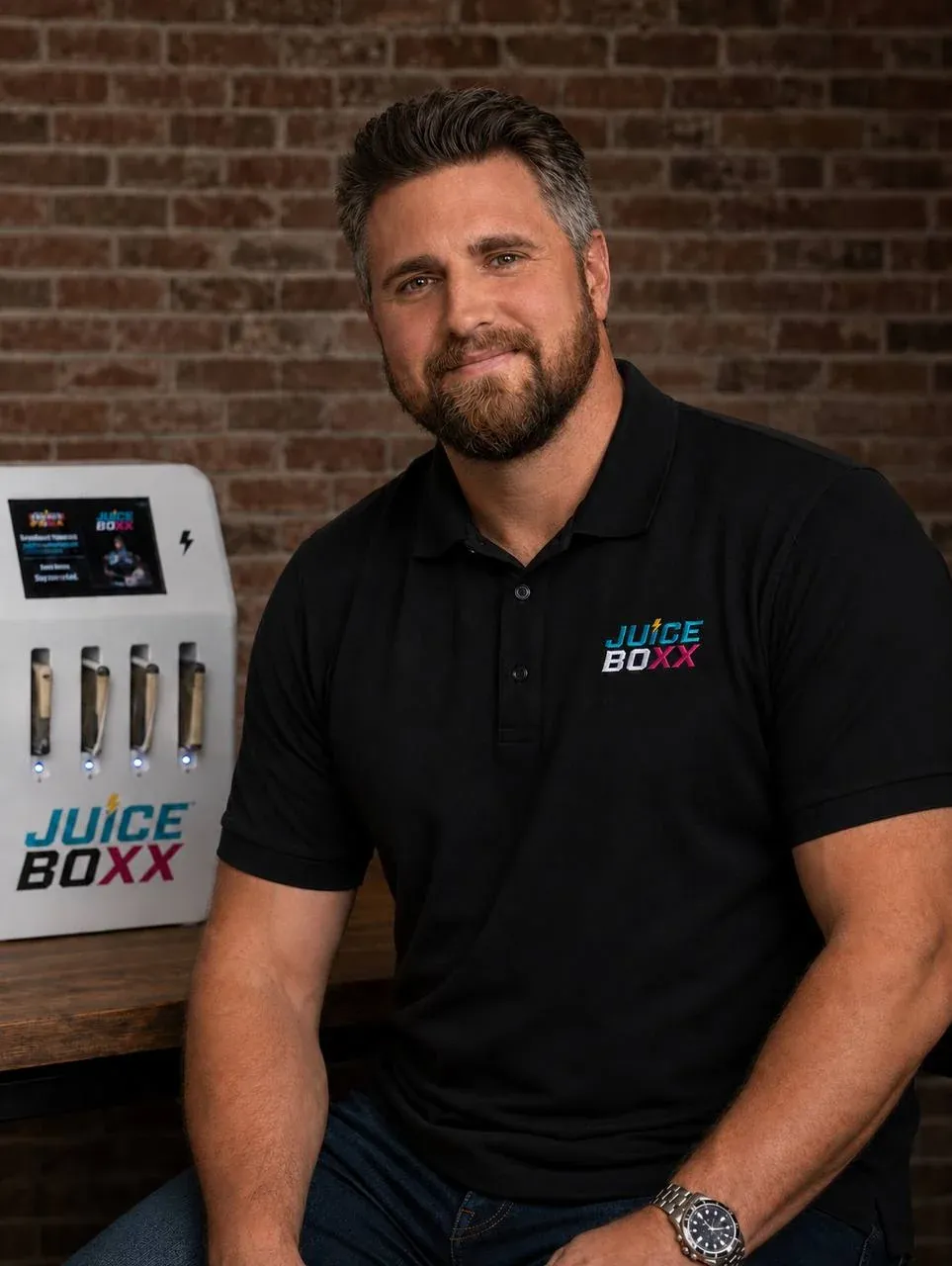 Andrew Crisp, owner of Juiceboxx, seated beside a charging station